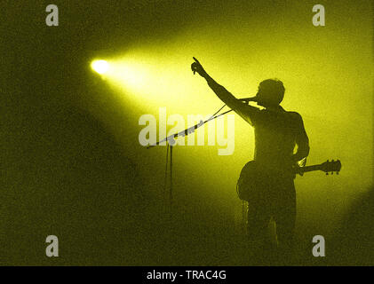 Une silhouette d'un guitariste professionnel leader de singer sur scène avec son bras jusqu'en remerciant la foule dans le microphone pour une soirée merveilleuse Banque D'Images