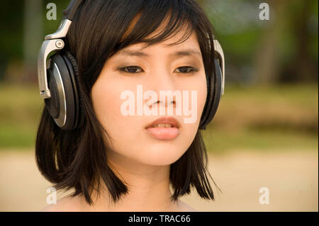 Portrait d'un jeune moderne Asian woman wearing big headphones listening to music Banque D'Images