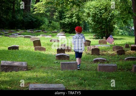 Plymouth Meeting, PA, USA - juin 1, 2019 : un jeune garçon, en bonnet rouge passe entre tombes cimetière Quaker. Banque D'Images