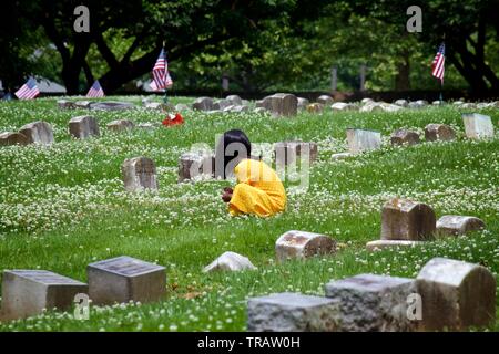 Plymouth Meeting, PA, USA - 1 juin 2019 : Une jeune fille en robe jaune fleurs prend entre les tombes dans un cimetière Quaker. Banque D'Images