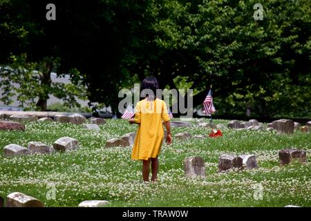 Plymouth Meeting, PA, USA - 1 juin 2019 : Une jeune fille en robe jaune fleurs prend entre les tombes dans un cimetière Quaker. Banque D'Images