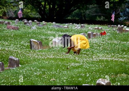 Plymouth Meeting, PA, USA - 1 juin 2019 : Une jeune fille en robe jaune fleurs prend entre les tombes dans un cimetière Quaker. Banque D'Images