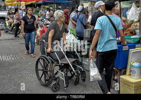 Femme handicapée en fauteuil roulant à un commerçant avec la Thaïlande street market Banque D'Images