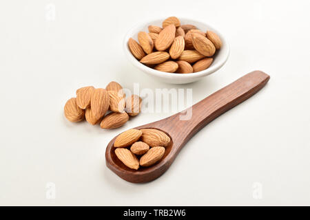 Cuillère en bois et d'amandes dans un bol blanc isolé sur fond blanc Banque D'Images