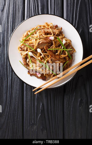 Beef Chow Fun un aliment plat cantonais, fabriqué à partir de sauté de boeuf, légumes et nouilles de riz larges gros plan sur la plaque sur la table en bois. La verticale Banque D'Images