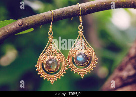 D'oreilles en métal laiton avec pierre labradorite minéraux naturels hanging on tree branch Banque D'Images