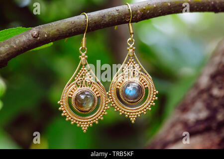 D'oreilles en métal laiton avec pierre labradorite minéraux naturels hanging on tree branch Banque D'Images