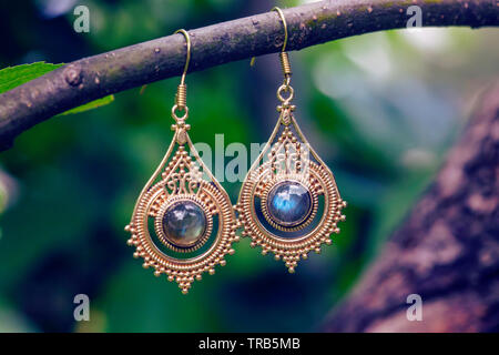 D'oreilles en métal laiton avec pierre labradorite minéraux naturels hanging on tree branch Banque D'Images