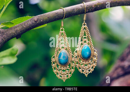 D'oreilles en métal laiton avec pierre larymar minérales naturelles hanging on tree branch Banque D'Images