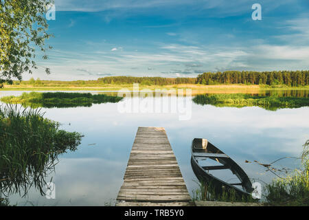 Vieux Bateau de pêche en bois abandonnés près de Pier en été, lac ou rivière. Belle journée ensoleillée d'été ou en soirée. Barque abandonnée. La nature russe. Banque D'Images