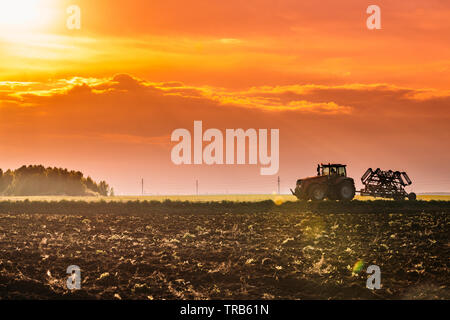 Le tracteur sur route au printemps. Début de saison Printemps agricoles. Le cultivateur tiré par un tracteur à la campagne Domaine Rural Landscape en vertu de l'al. Banque D'Images