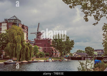 Grand canal arboré avec bâtiments en brique et bateaux amarrés à Amsterdam. L'activité culturelle de la ville avec d'énormes, les canaux et les ponts en Pays-Bas. Banque D'Images
