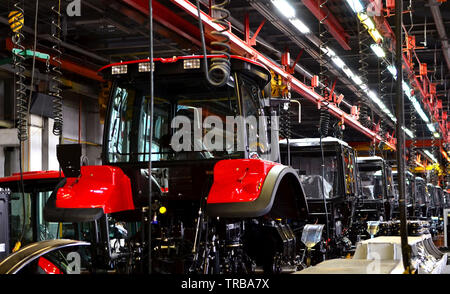 Fabrication du tracteur. Ligne de Montage à l'intérieur de l'usine de machines agricoles. L'installation de pièces sur le corps du tracteur - Image Banque D'Images