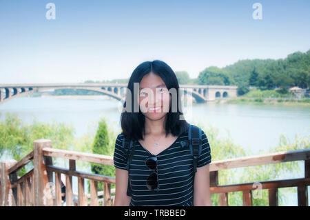 Une bonne femme chinoise avec la rivière Yi et pont en arrière-plan de longmen à Luoyang Chine lors d'une journée ensoleillée. Banque D'Images
