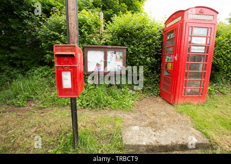 Une boîte de téléphone rouge en milieu rural Dorset qui a été utilisé comme un échange de livres. Le téléphone fort abrite aussi un défibrillateur et est à côté d'un village avis b Banque D'Images