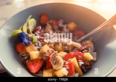 Petit-déjeuner sain porridge concept : avoine avec flocons de noix de coco, fraise, banane et mangue morceaux servis avec du yaourt grec et de miel naturel Banque D'Images