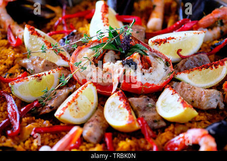 Close up au-dessus de la partie supérieure de l'image d'ingrédients mûres préparés servis cuisine traditionnelle espagnole paella, des couleurs vives. Lave garnie avec slic citron Banque D'Images