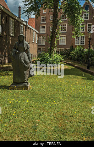 Maisons de briques typiques, statue et jardin verdoyant à Begijnhof à Amsterdam. L'activité culturelle de la ville avec d'énormes, les canaux et les ponts en Pays-Bas. Banque D'Images