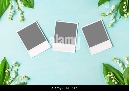 Cartes photo vierge pour instagram dans cadre fait de lis de la vallée des fleurs sur table en bois bleu. Télévision. vue d'en haut. fond de mariage Banque D'Images