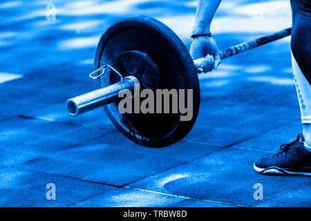 La préparation de sa femme crossfit haltérophilie d'entraînement avec un haltère lourd. Couleur bleu Banque D'Images