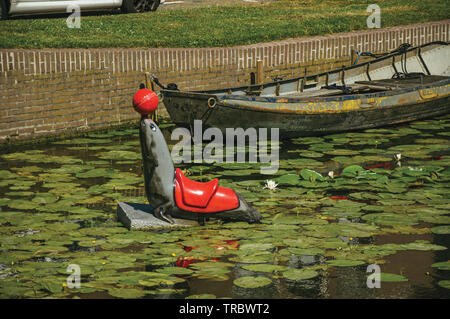 Statue d'étanchéité avec balle dans le nez sur le canal de l'eau avec des plantes aquatiques à Weesp. Agréable village plein de canaux et green en Pays-Bas. Banque D'Images