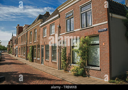 Maisons de briques populaires dans une étroite rue vide sous un ciel bleu à Weesp. Agréable village plein de canaux et green en Pays-Bas. Banque D'Images