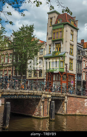 Pont sur canal avec des bicyclettes, balustrade en fer et de vieux bâtiments à Amsterdam. L'activité culturelle de la ville avec d'énormes, les canaux et les ponts en Pays-Bas. Banque D'Images