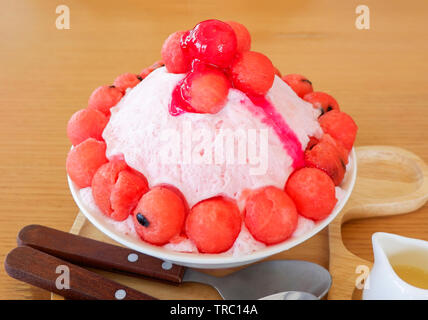 Dessert sucré Bingsu korea style rasé bingsoo / pastèque fruits sur glace topping avec du lait et du sirop de fruits dans le bac sur la table en bois Banque D'Images