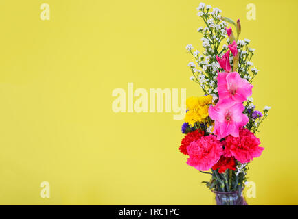 Bouquet de fleurs de source fraîche avec des plantes colorées et belles fleurs carnation glaïeul divers sur fond jaune Banque D'Images