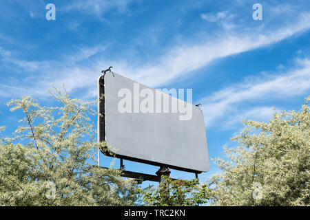 Blank billboard toile avec copie espace de publicité, immersive contexte dans le ciel bleu, entourée par les arbres. Banque D'Images