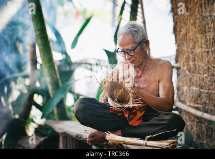 La vie Asie vieux grand-père oncle travaillant dans accueil / homme sérieux âgés vivant dans la campagne de la vie des populations rurales dans la Thaïlande bambou tissage bask Banque D'Images