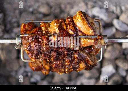 Épaule de porc délicieux cuit sur lent sur une pointe de charbons rôtisserie. Banque D'Images