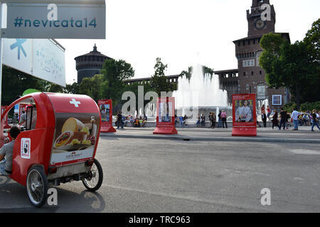 Milan/Italie - 1 juin 2015 : vue d'un trishaw moderne suisse rouge garée dans le Castello Sforzesco de Milan place avec fontaine, des murs et des tours. Banque D'Images