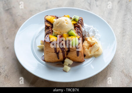 Glace vanille crème de miel pain grillé avec des tranches de fruits et sauce au chocolat on white plate Banque D'Images