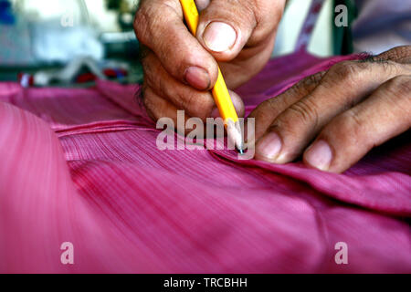 Photo d'une paire de mains d'un tailleur et de mesure rendant les marques sur une robe Banque D'Images