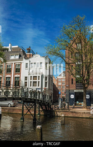 Balustrade en fer avec Pont sur canal bordé d'arbres et de vieux bâtiments à Amsterdam. L'activité culturelle de la ville avec d'énormes, les canaux et les ponts en Pays-Bas. Banque D'Images