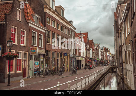 Rue commerçante avec canal, les bâtiments en brique et des vélos à Delft. Village gracieux plein de canaux et de l'architecture gothique en France. Banque D'Images