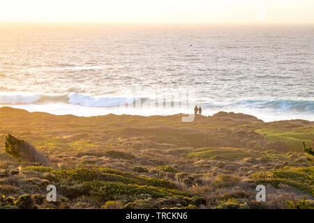 Couple heureux pour le coucher du soleil avec une incroyable vue sur l'océan Pacifique de Big Sur, Californie Côte depuis une falaise. Banque D'Images