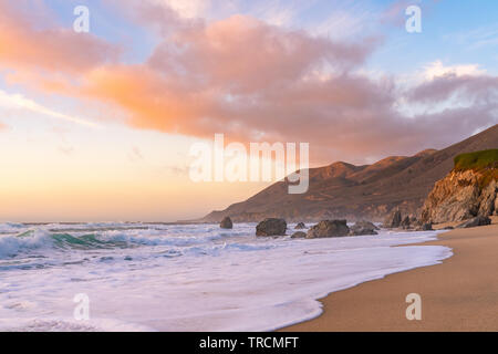 Coucher du soleil le long d'une plage de sable avec des montagnes dans le long de la côte dans la région de Big Sur, en Californie. Banque D'Images