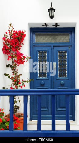 Bleu avec une porte de couleur rose lumineux bougainvilliers en pot à Santorin, Grèce. Banque D'Images