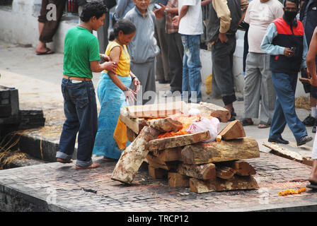 Un rite de la crémation hindou au Népal. Le samskara montre le corps enveloppé dans un tissu safran sur un bûcher. Temple de Pashupatinath, Katmandou, Népal Banque D'Images