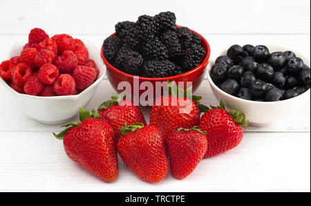 Fruits de la forêt de petits fruits sur une table de bois blanc Banque D'Images