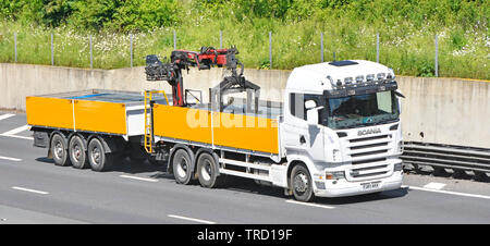 Vue latérale de l'avant & camions poids lourds Scania remorque Remorquage pavés chargés de matériaux de construction de la grue de déchargement du camion est à la livraison au site UK d'autoroute Banque D'Images