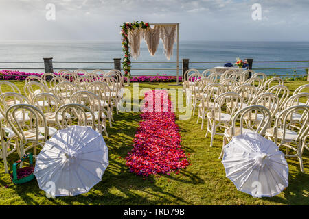 Arch dans mariage style Boho près de l'océan de cérémonie décoré de macrame et fleurs fraîches. Chaises longues, parasols et l'allée de pétales roses et rouges. Bali Banque D'Images