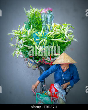 Les vendeurs de rue sont rapidement du vélo à travers la rue pour trouver des clients dans le petit quartier de Hanoi, Vietnam Banque D'Images