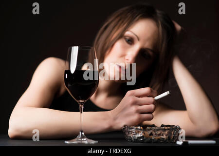 Portrait d'un déprimé et femme désalcoolisée avec un verre de vin et une cigarette dans ses mains Banque D'Images