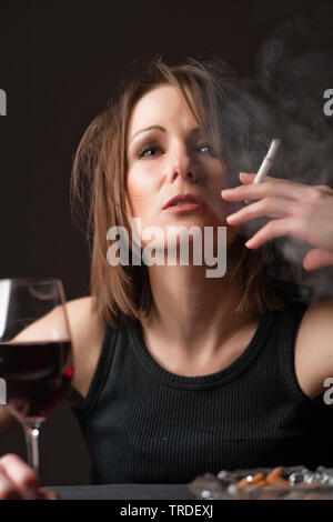 Portrait d'une femme désalcoolisée déprimé avec un verre de vin et une cigarette dans ses mains Banque D'Images