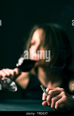 Portrait d'une femme ivre avec un verre de vin et une cigarette dans ses mains Banque D'Images