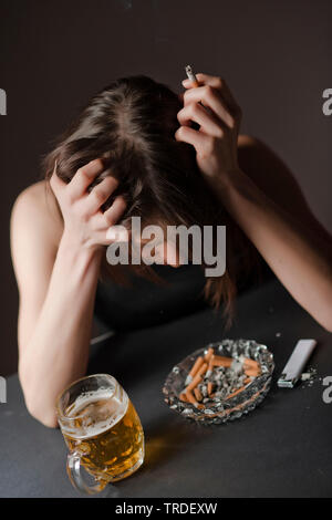 Portrait d'un déprimé et femme désalcoolisée avec un verre de bière et une cigarette dans ses mains Banque D'Images