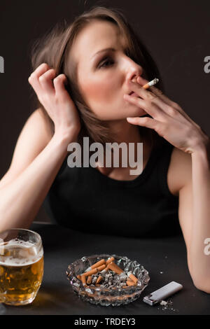 Portrait d'un déprimé et femme désalcoolisée avec un verre de bière et une cigarette dans ses mains Banque D'Images